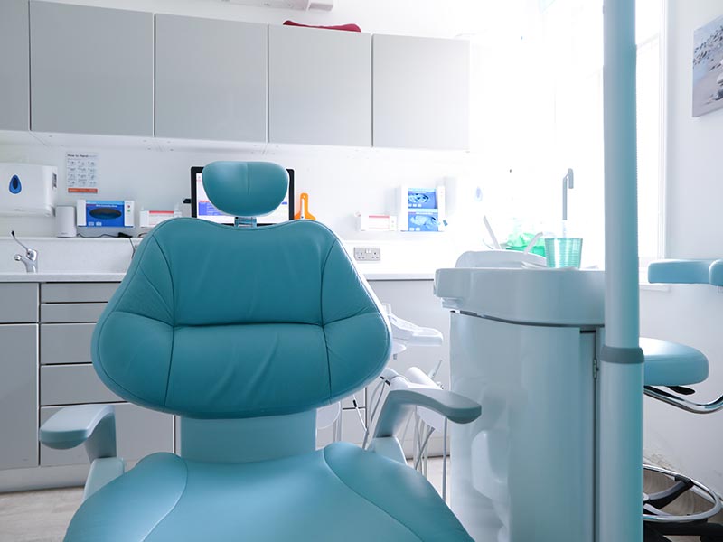 blue dental chair and equipment in bright and clean treatment room